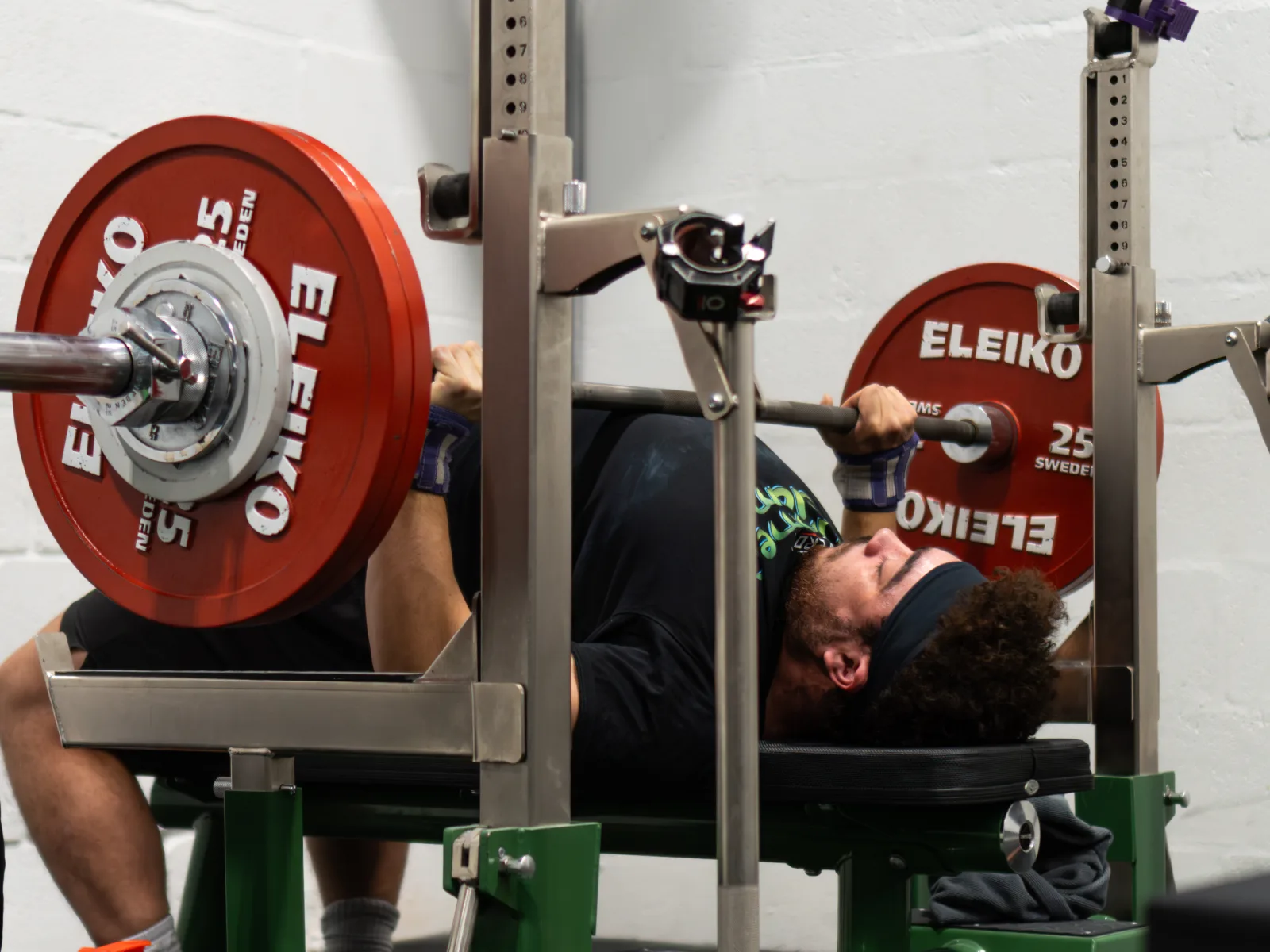 A lifter pressing a heavy bench press in the competition rack at ZeroW Wales