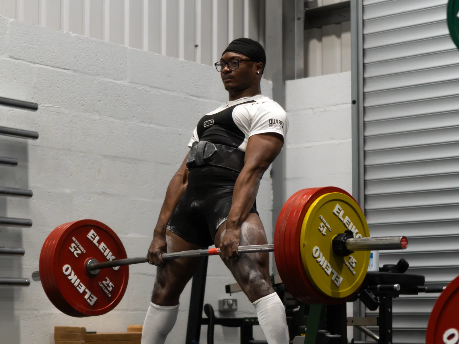 A lifter locking out a deadlift on the platform at ZeroW Wales
