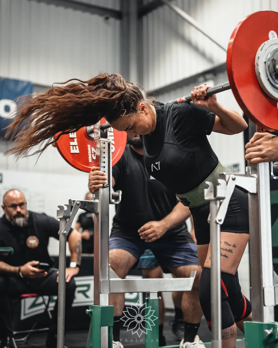 A lifter setting up for a squat, hair flying, at Kilo Classic III