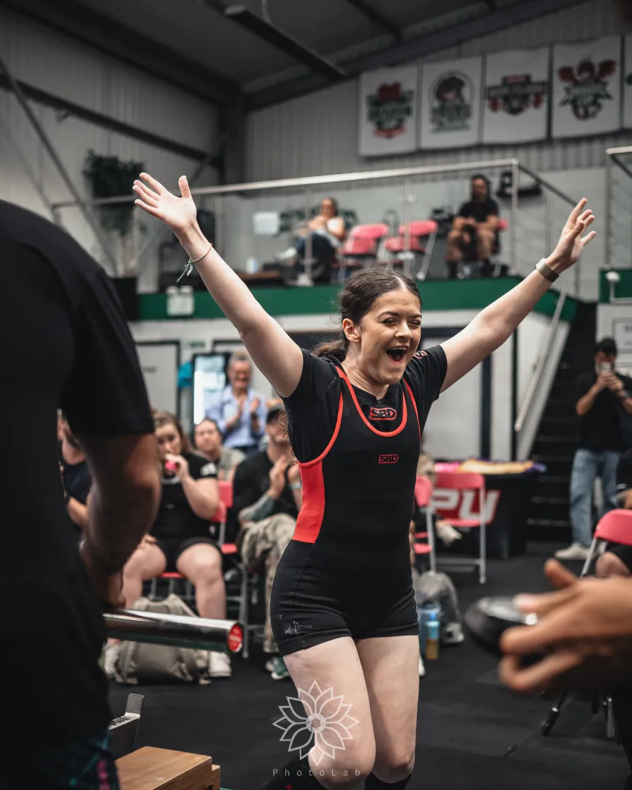 A lifter throwing both arms up in celebration as the crowd cheers